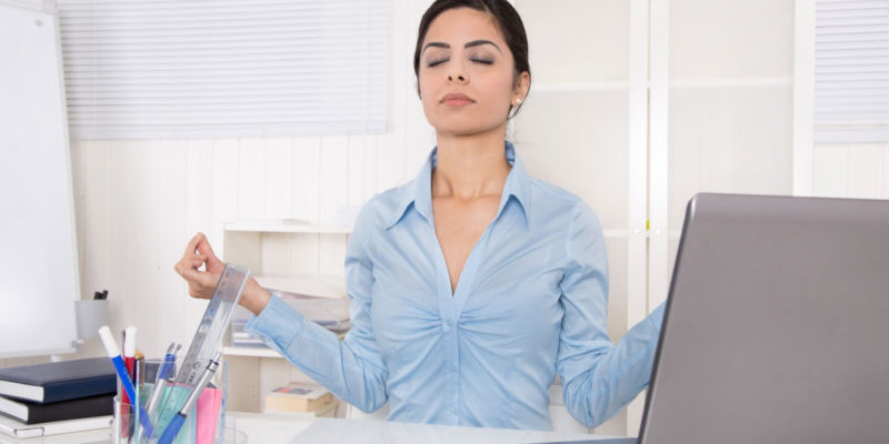 foto de mulher meditando na mesa de trabalho