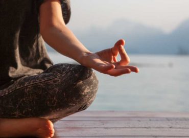 foto de uma mulher meditando com um mar ao fundo