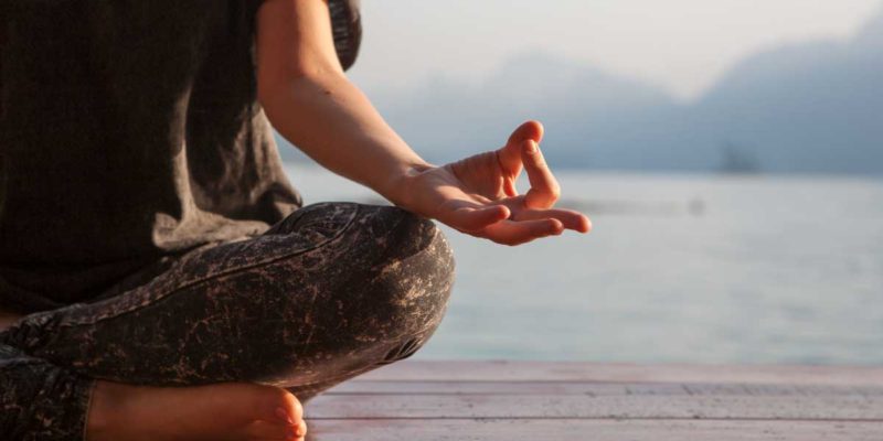 foto de uma mulher meditando com um mar ao fundo