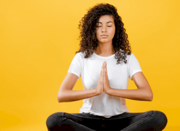 Foto de uma mulher negra meditando em fundo amarelo